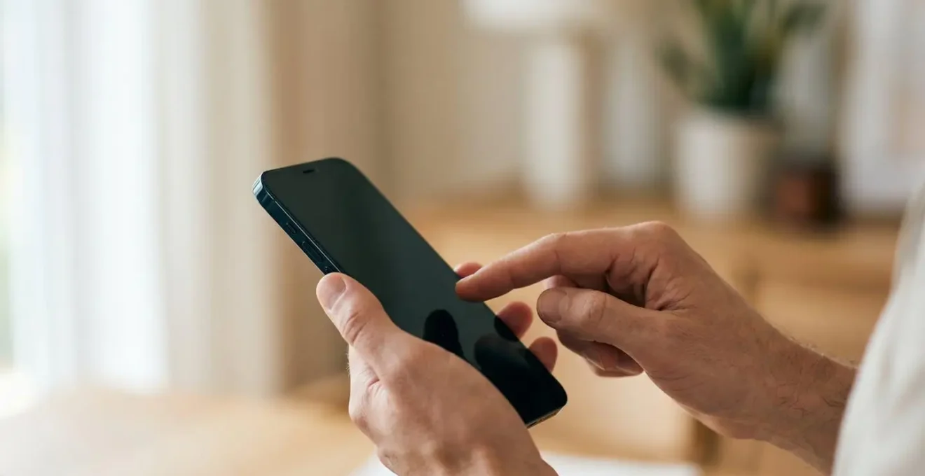 Composition minimaliste montrant des mains tenant un téléphone pour déclarer un sinistre dans un environnement lumineux et épuré