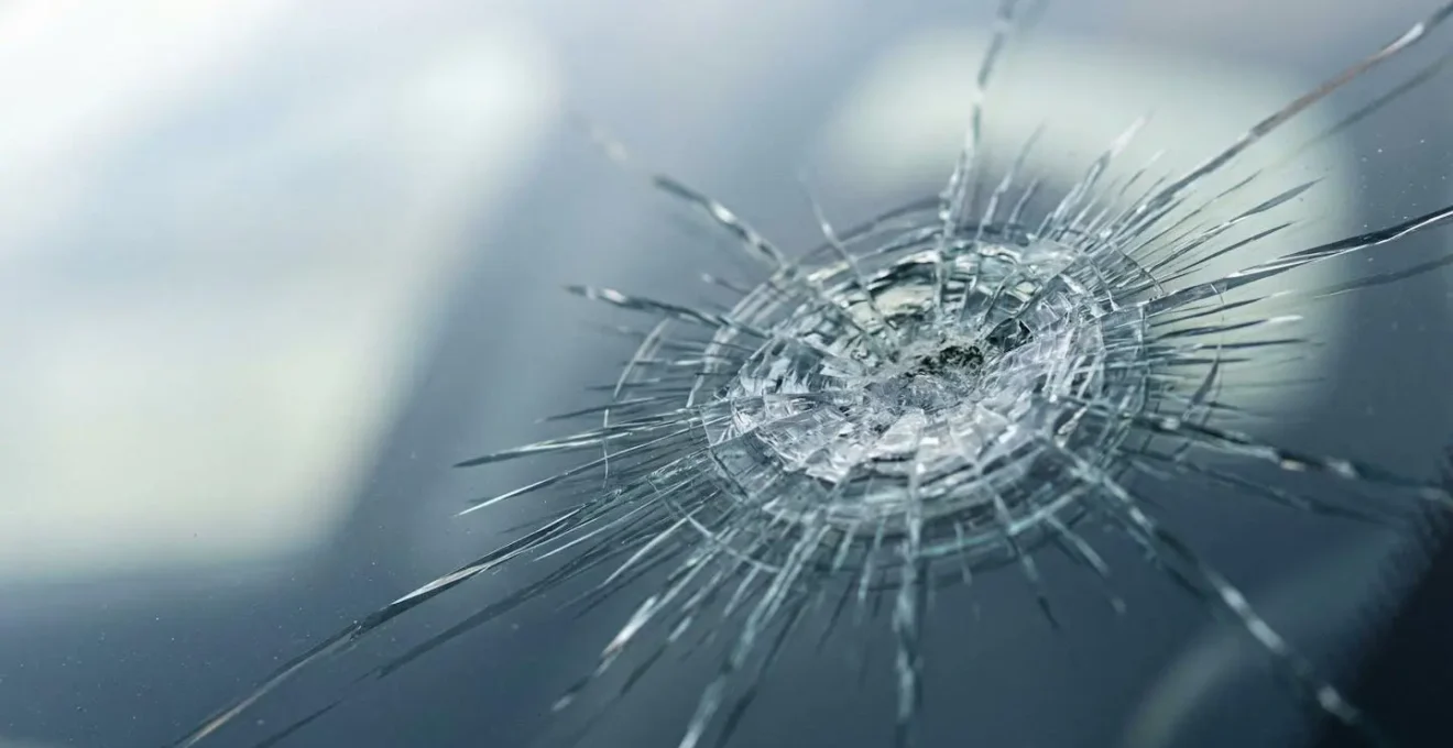 Gros plan détaillé d'un impact de gravillon sur un pare-brise automobile moderne avec système ADAS intégré